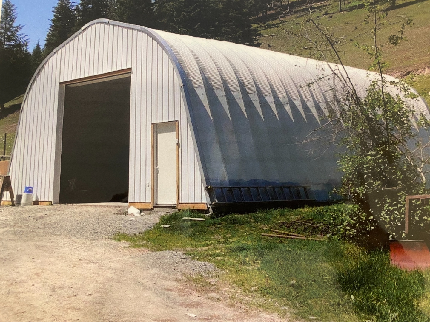 A Series steel building with open bay in wooded setting
